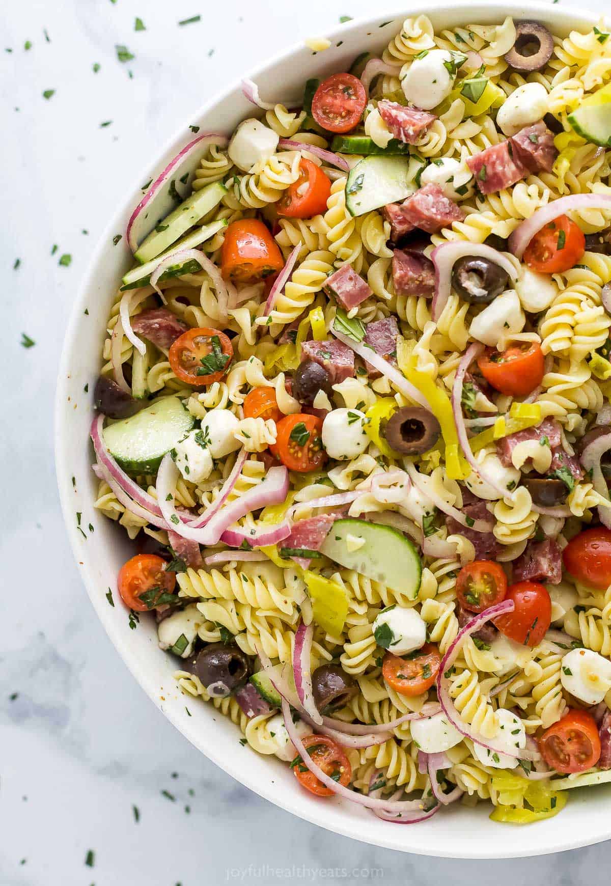 This Classic Italian Pasta Salad will have everyone asking for the recipe! It's a healthy, refreshing side dish that feels like comfort food. A large bowl of pasta salad on a marble kitchen countertop