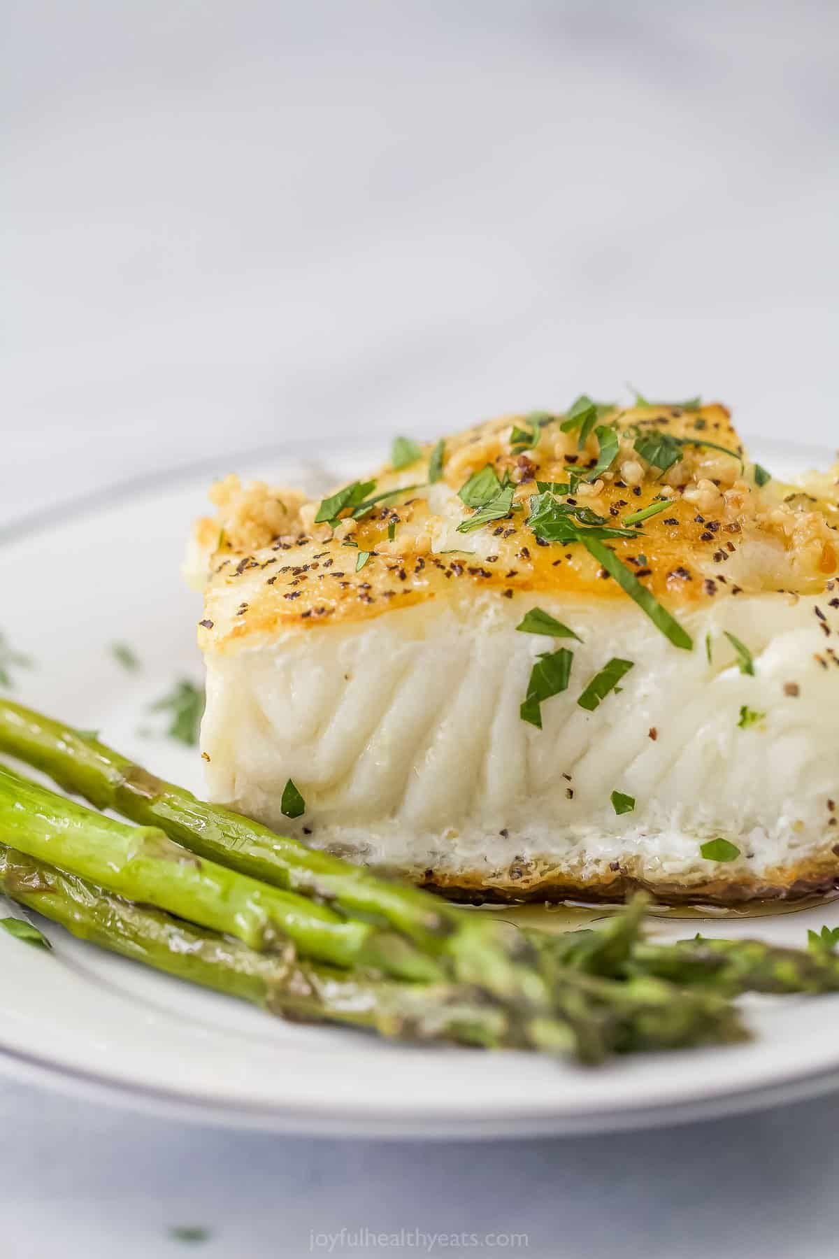 Pan Seared Chilean Sea Bass is flaky, tender, and has a buttery golden crust. Lemon and garlic are also added to this simple seafood dish. Seared sea bass with asparagus on the side