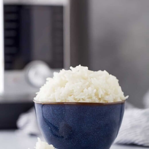 A bowl of Jasmine rice with chopsticks on a countertop