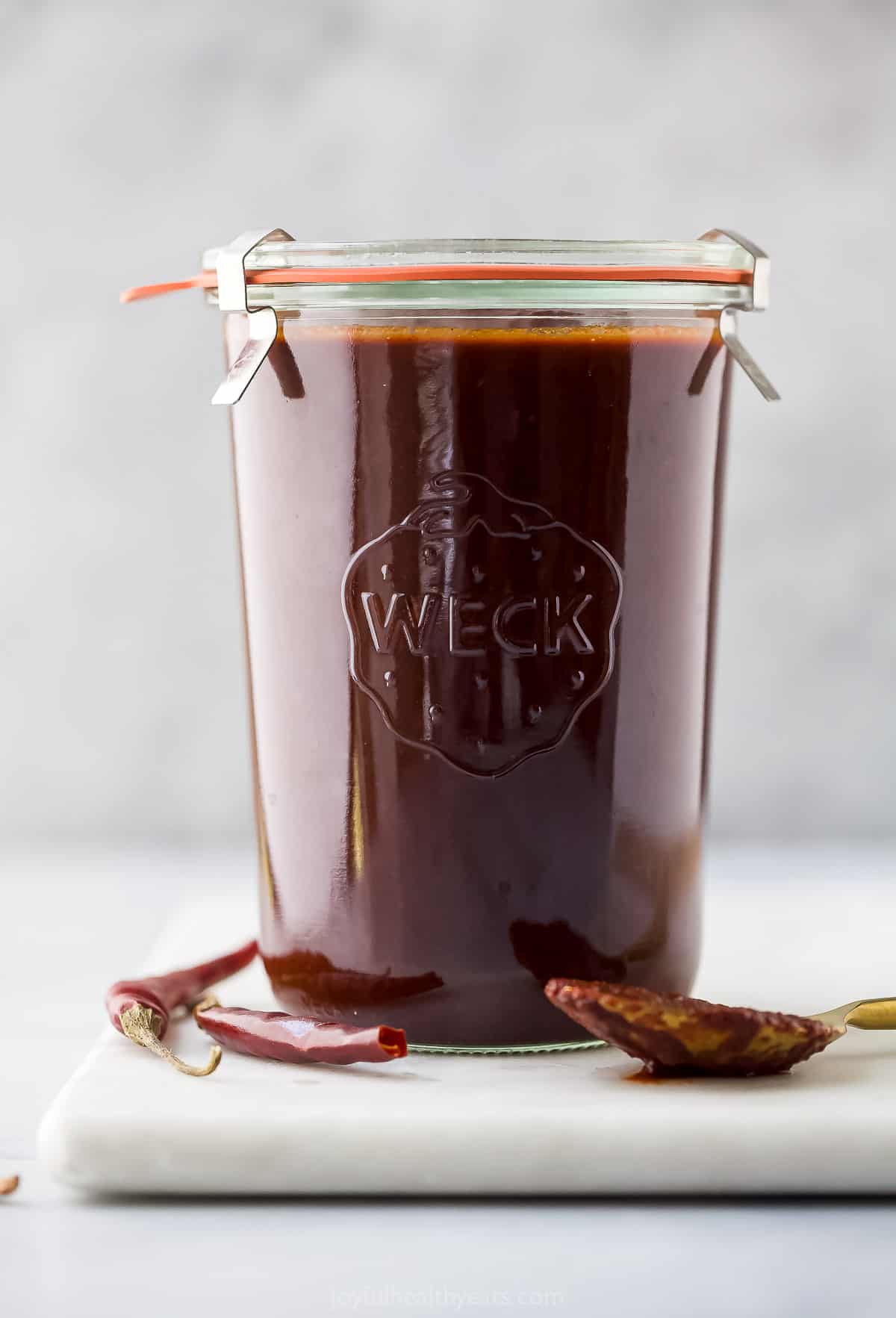 This Homemade Red Enchilada Sauce is smokey, spicy, slightly sweet, and perfectly rich. Its authentic flavor goes great with so many dishes. glass jar with red enchilada sauce