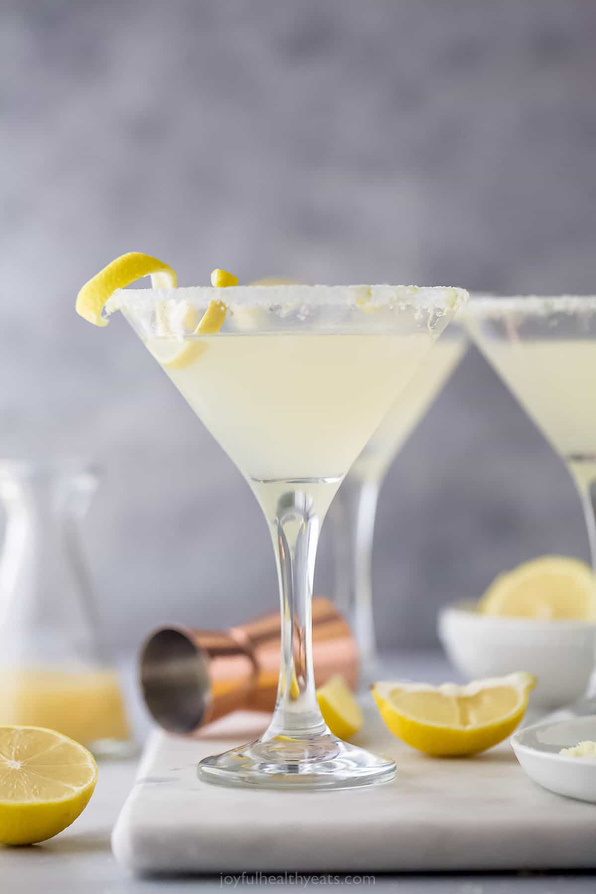 a lemon drop martini with a lemon rind garnish and sugared rim