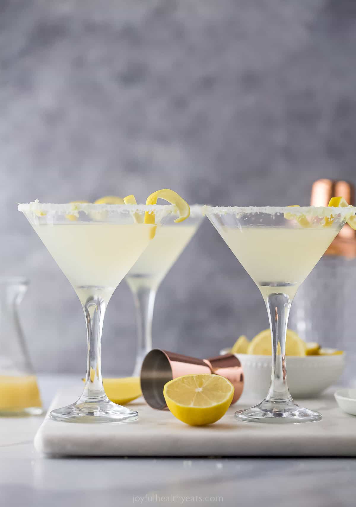 This Lemon Drop Martini is tart, refreshing, and a little sweet from the sugar rim! Fresh lemon juice is used for the best-tasting cocktail. three martini glasses with a pale yellow cocktail