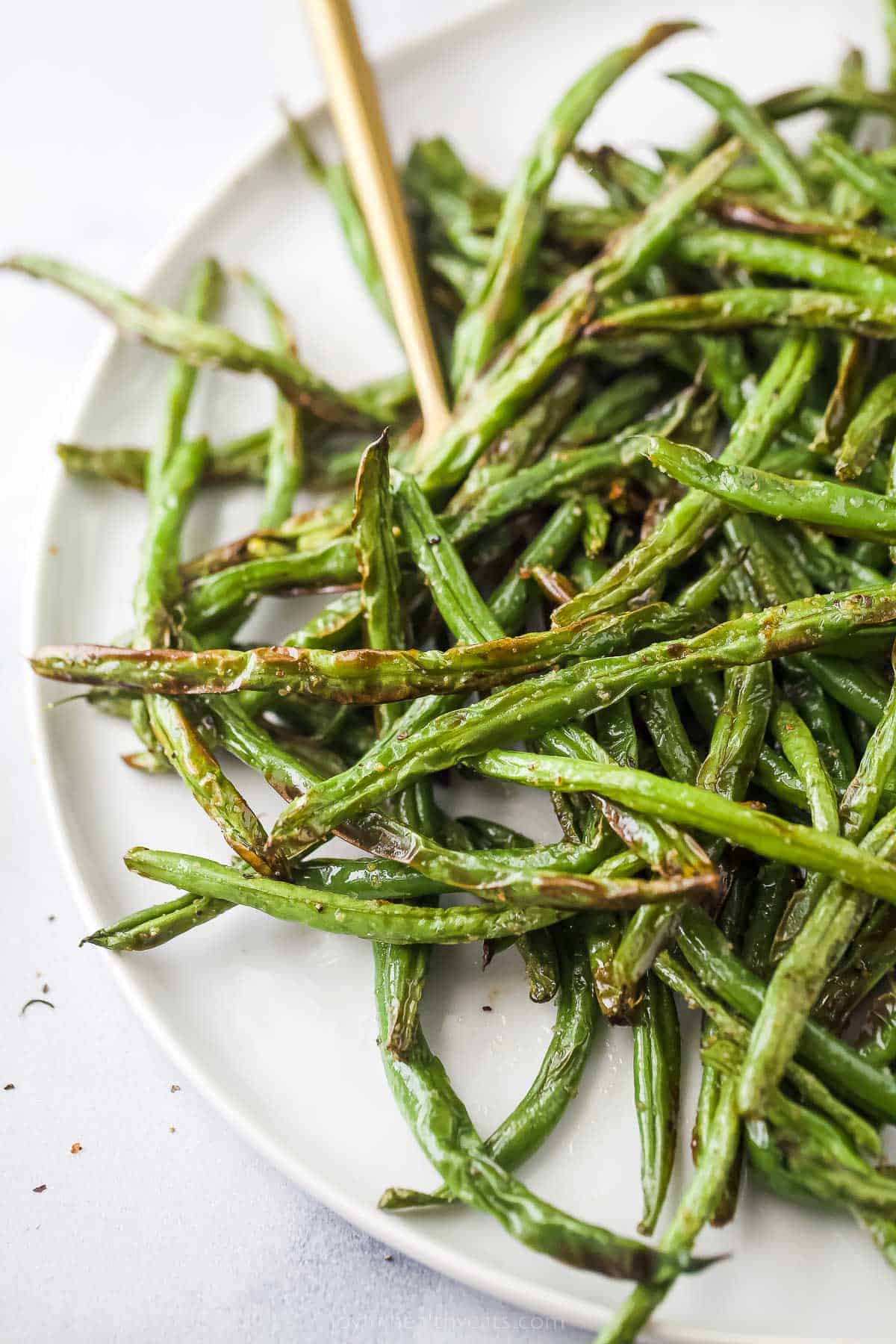 This Crispy Air Fryer Green Beans recipe is all you need for a quick, easy, and healthy side dish. Ready in under 15 minutes! fried green beans on a white plate