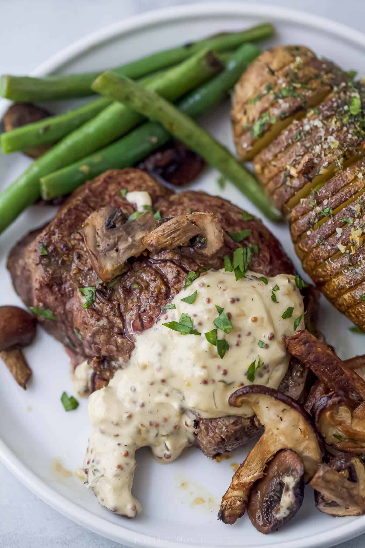 Filet Mignon with Mustard and Mushrooms is an elegant and easy steak dinner with sauteed mushrooms and a creamy dijon sauce. filet mignon with mustard and mushrooms on a plate with potato and green beans