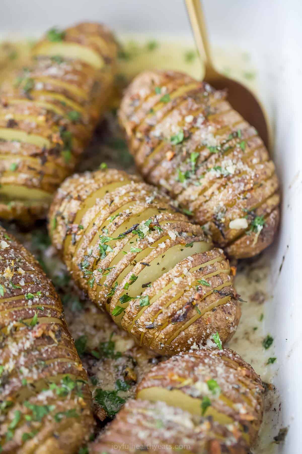 Garlic Herb Hasselback Potatoes are tender russet potatoes that are sliced thin, smothered in garlic herb butter, and then perfectly roasted. garlic herb hasselback potatoes in a baking dish