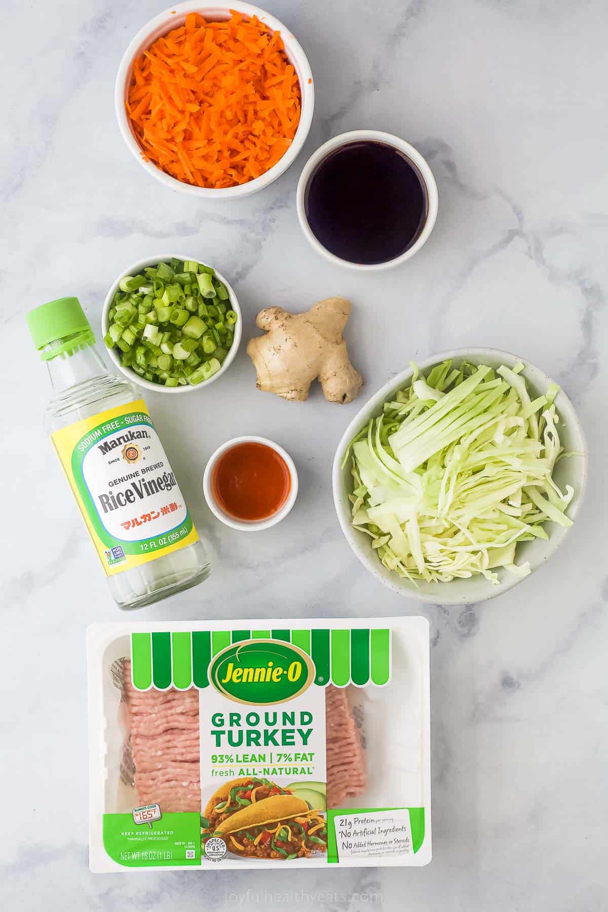 ground turkey, shredded cabbage, rice wine vinegar, ginger, soy sauce, scallions, carrots, and sriacha on a countertop
