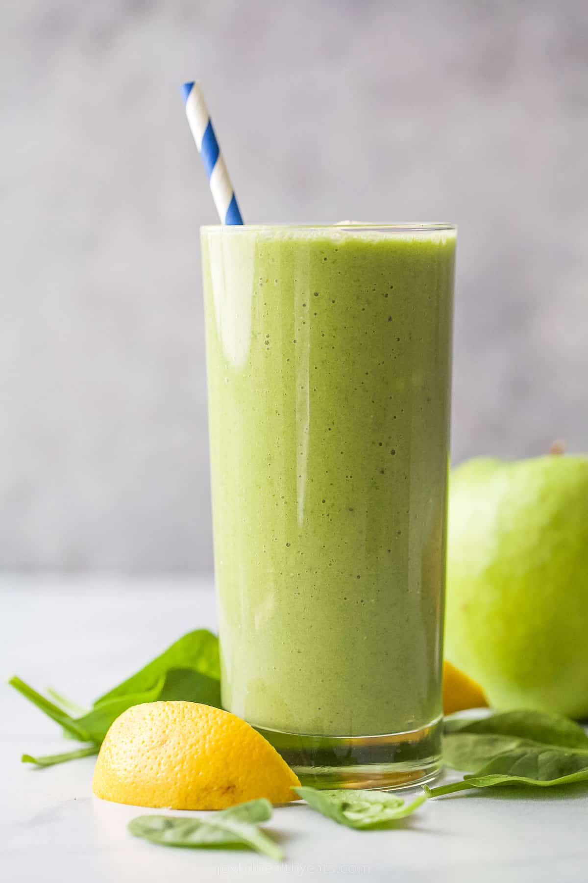 This Slimming Detox Smoothie is the perfect green smoothie! It has spinach, apples, pineapple, and banana, plus a dash of cinnamon! a glass with green smoothie and straw