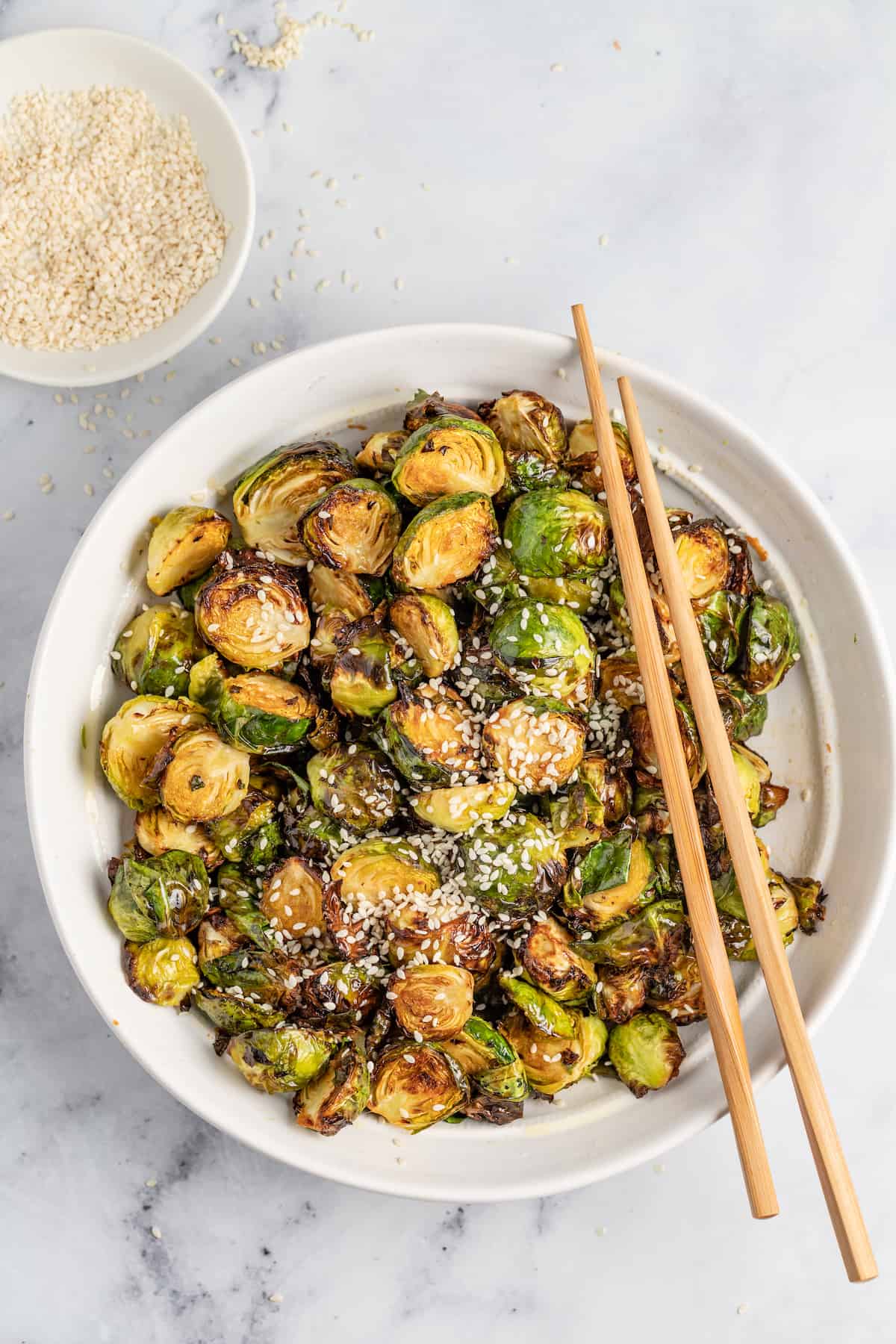 a bowl of crispy fried brussels sprouts and chopsticks