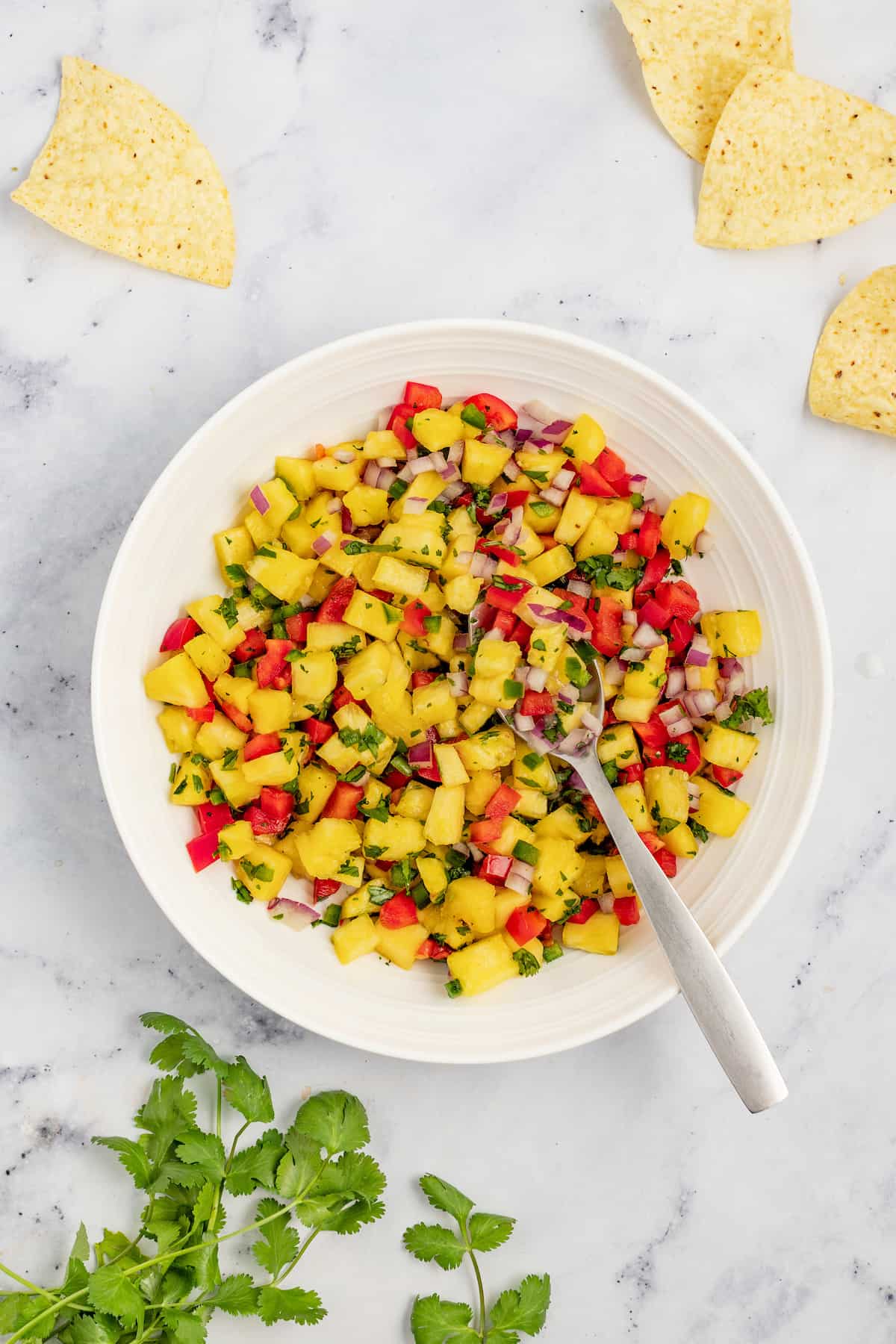 With bell pepper and jalapeño, this 15-minute pineapple salsa is a tangy, fruity, and crunchy addition to your all your meals. Pineapple salsa in a bowl with corn chips on the side.