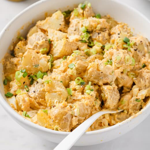Bowl of deviled egg potato salad with green onions.
