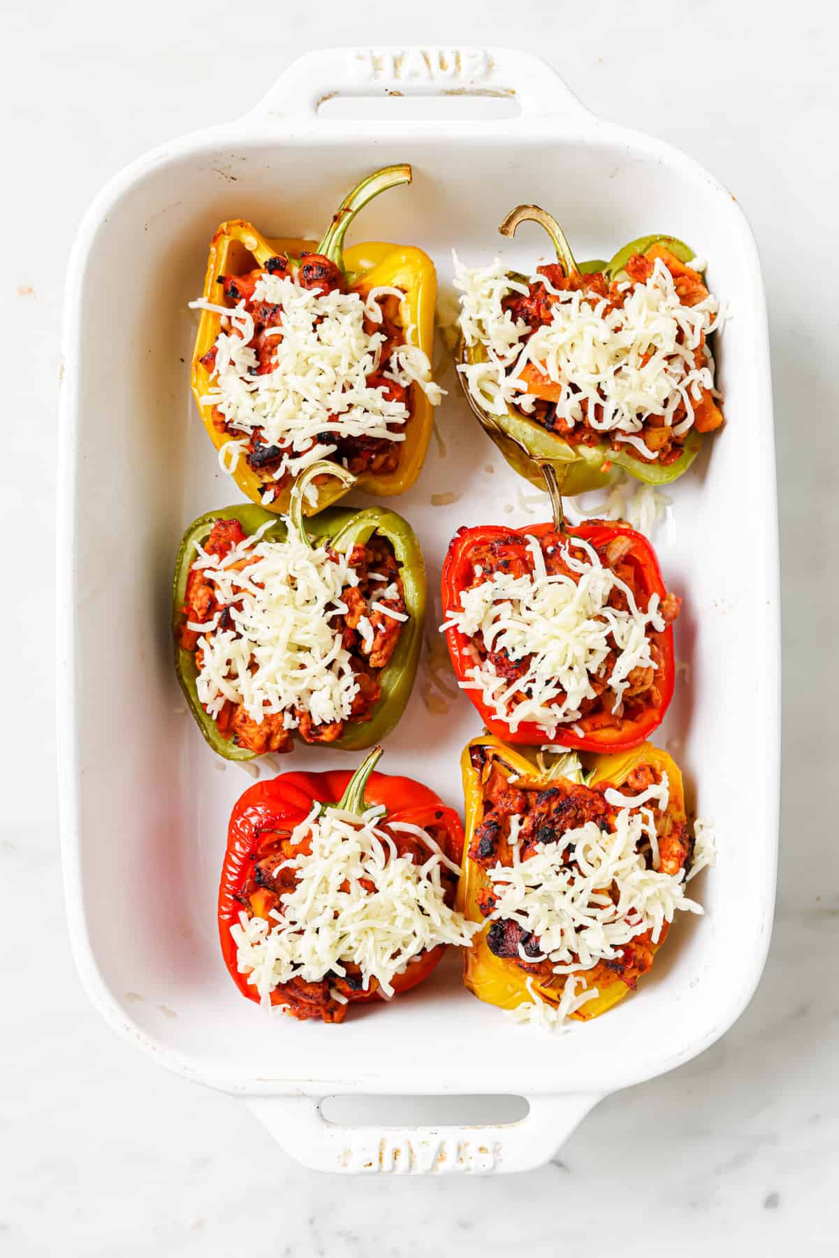 Ground turkey stuffed peppers with cheese in dish before baking