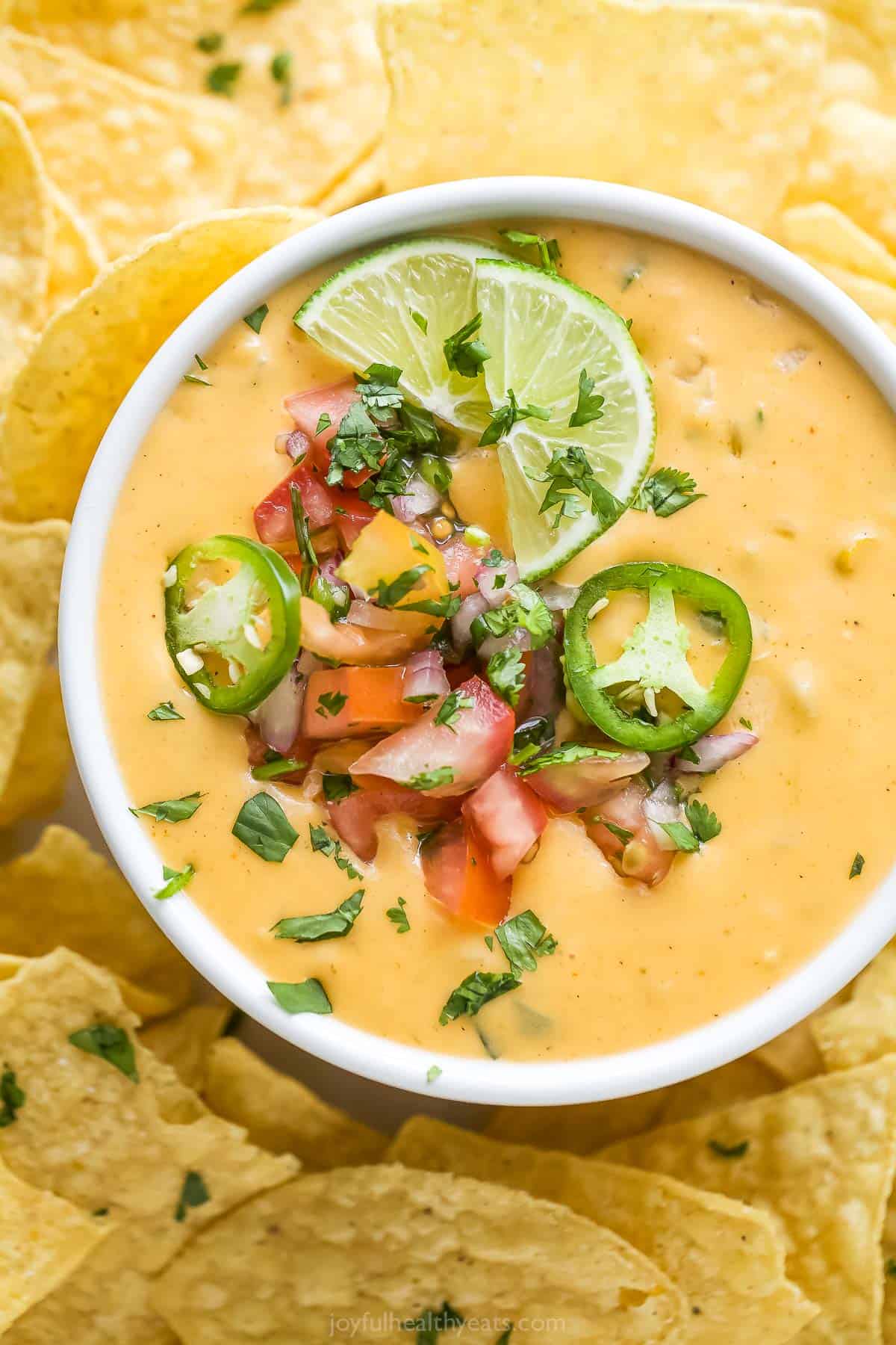 Made with two types of cheese, this spicy chile con queso is a creamy, velvety dip with sweet poblano peppers and fresh pico de gallo. Bowl of chile con queso with pico de gallo.