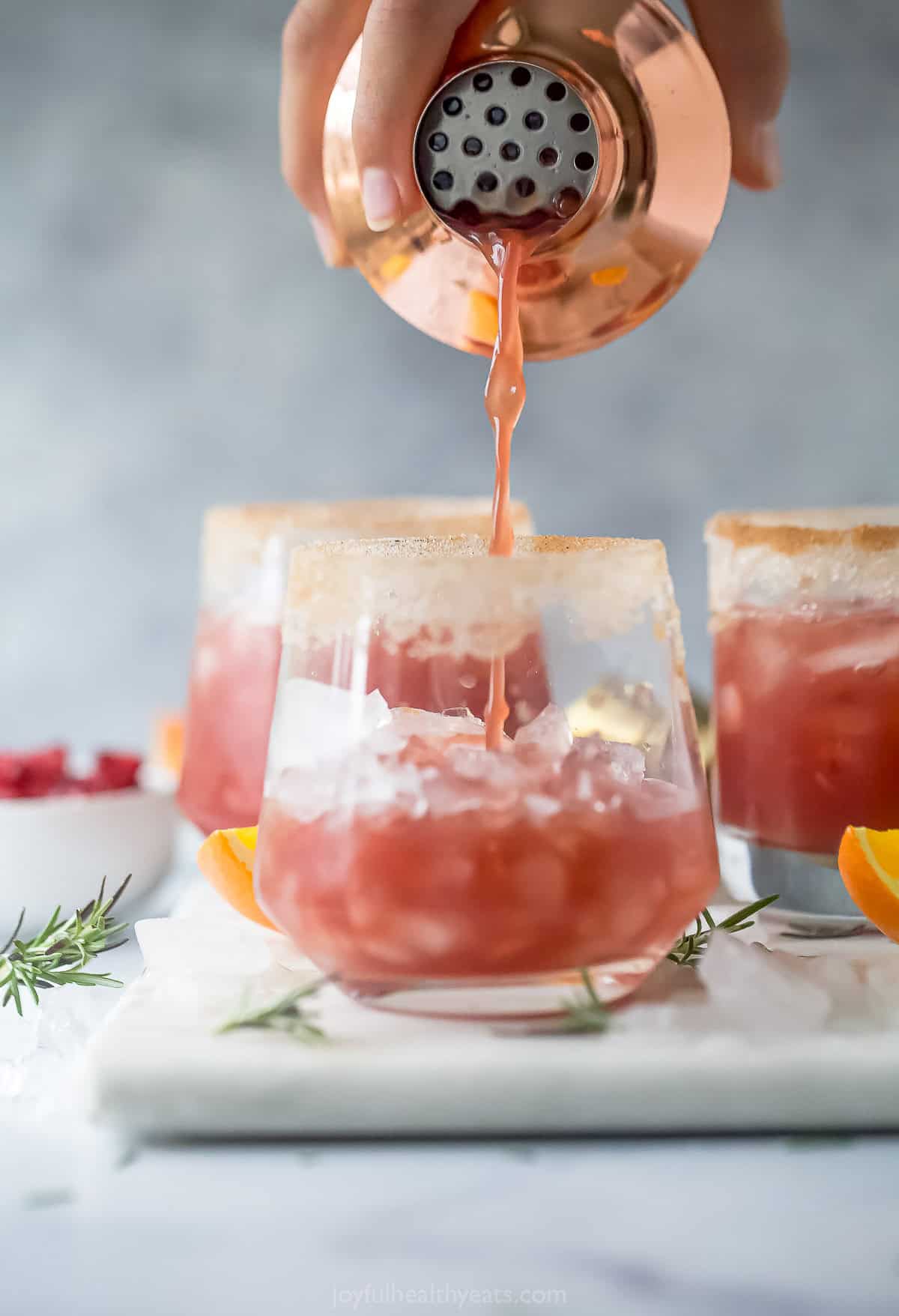 Pouring the cocktail into a cinnamon-sugar rimmed glass.