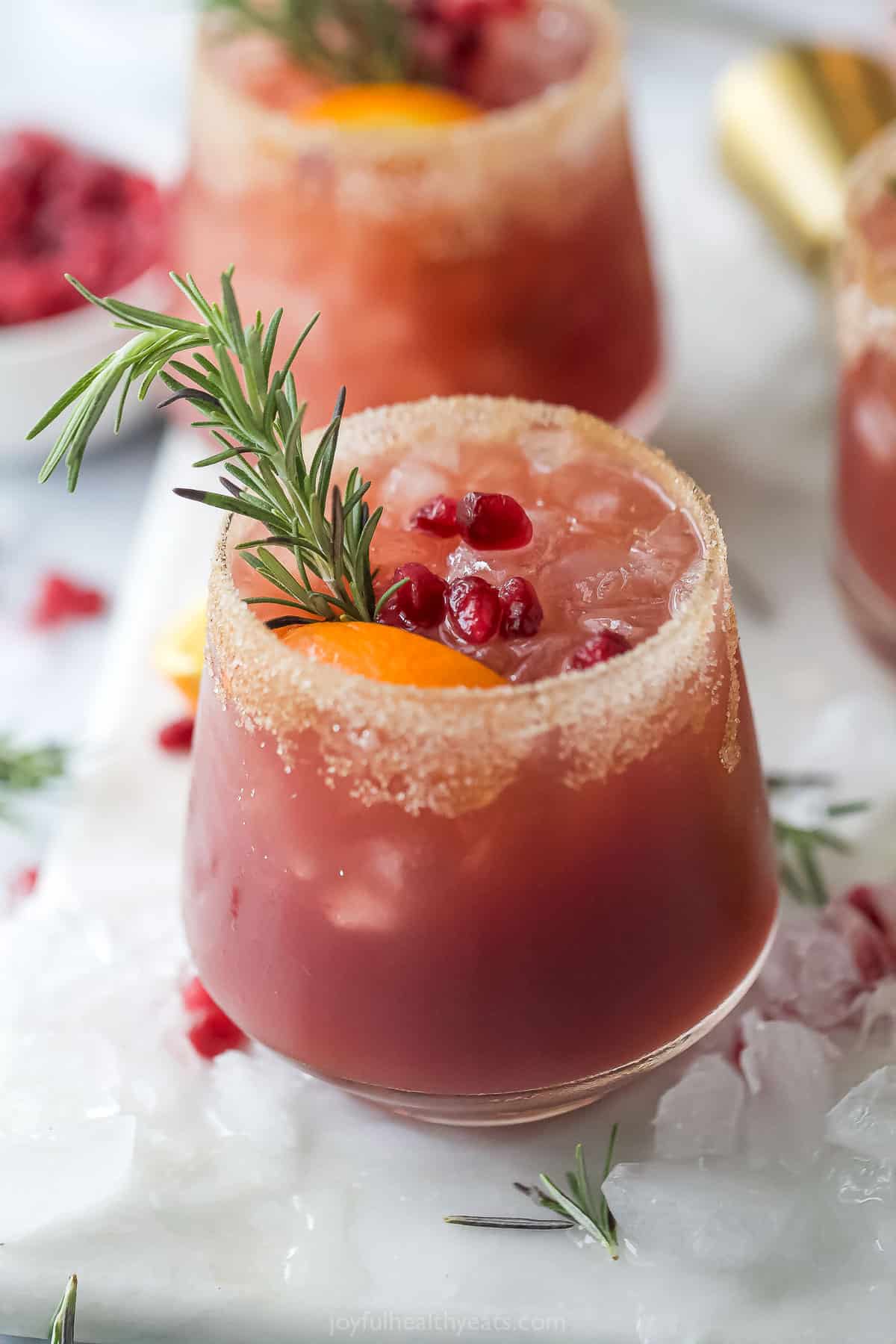 This 5-minute Christmas margarita recipe with fruit juice, tequila, and Grand Marnier is a sweet holiday cocktail for one. Close-up of a Christmas margarita with a cinnamon-sugar rim.