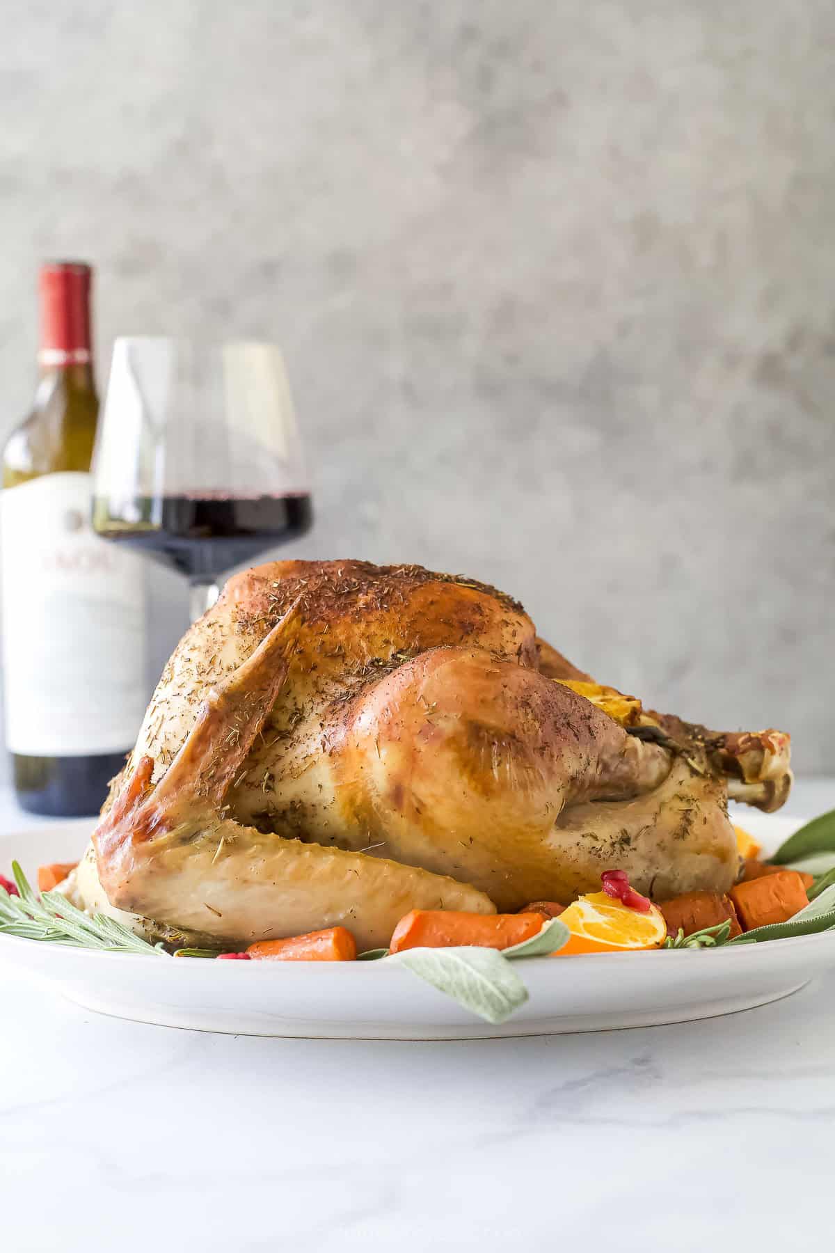 Roasted whole turkey with crispy skin on a serving platter with a glass of wine in the background.