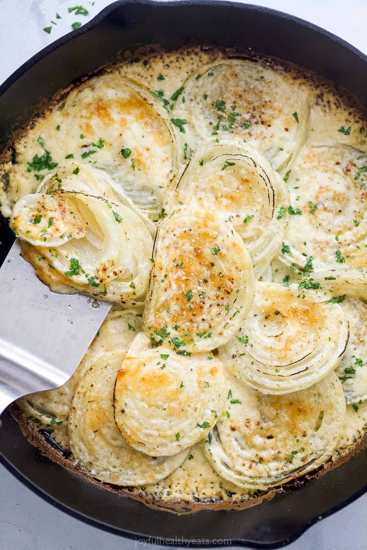 Grabbing some of the creamed onions recipe from the skillet with a spatula.