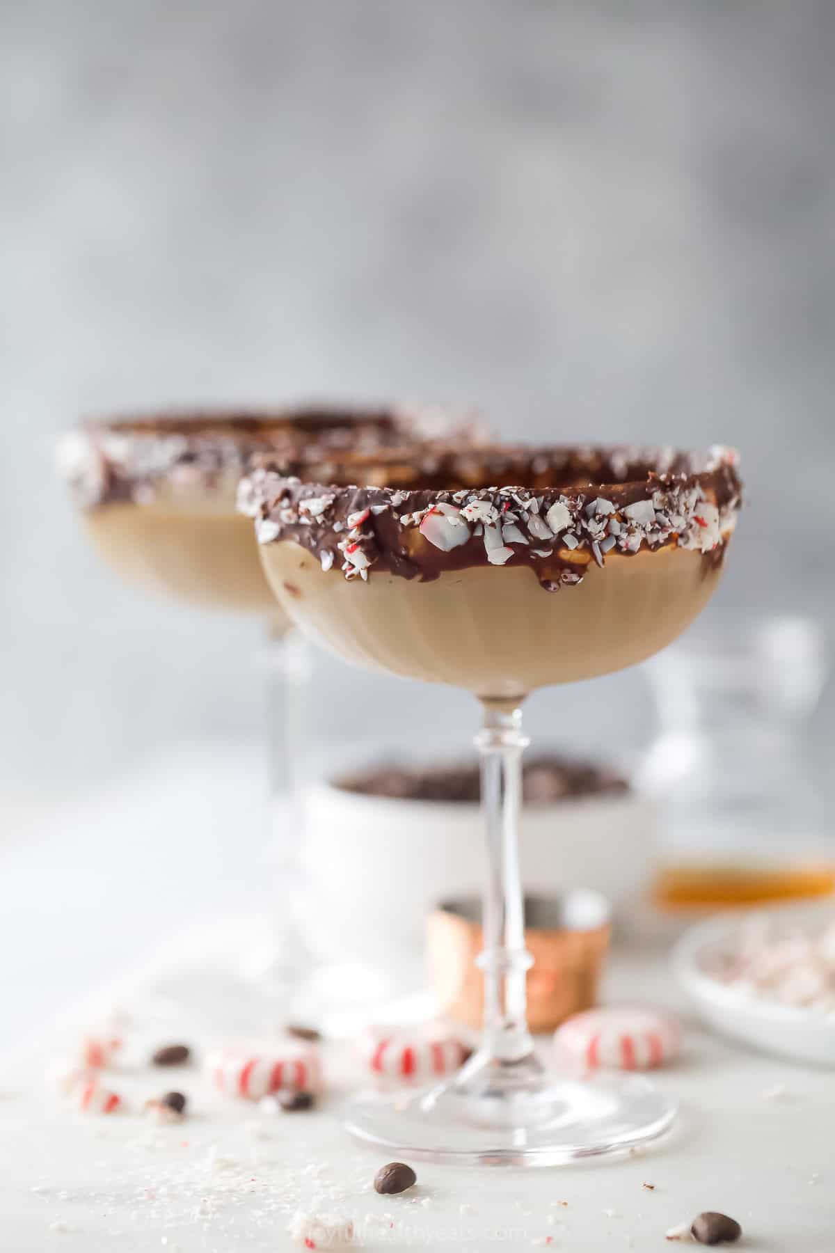 This 5-minute peppermint espresso martini recipe with a dark chocolate rim and coffee beans will be a holiday go-to. An icy peppermint espresso martini in a cocktail glass rimmed with dark chocolate and crushed peppermint candies.