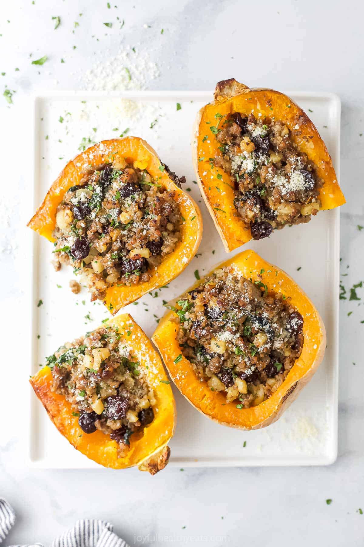 Four halves of butternut squash stuffed with homemade sausage-apple filling. 