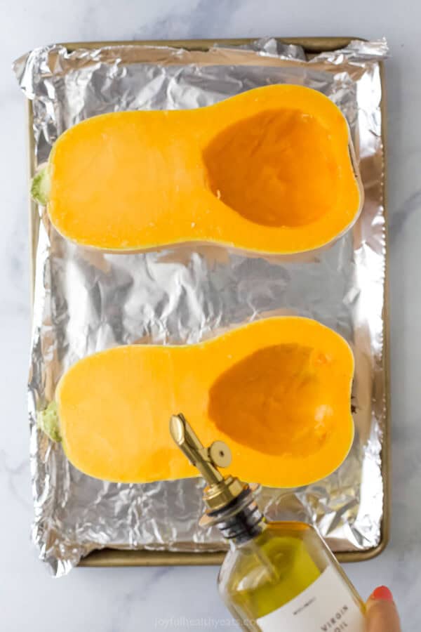 Drizzling the seeded butternut squashes with olive oil.