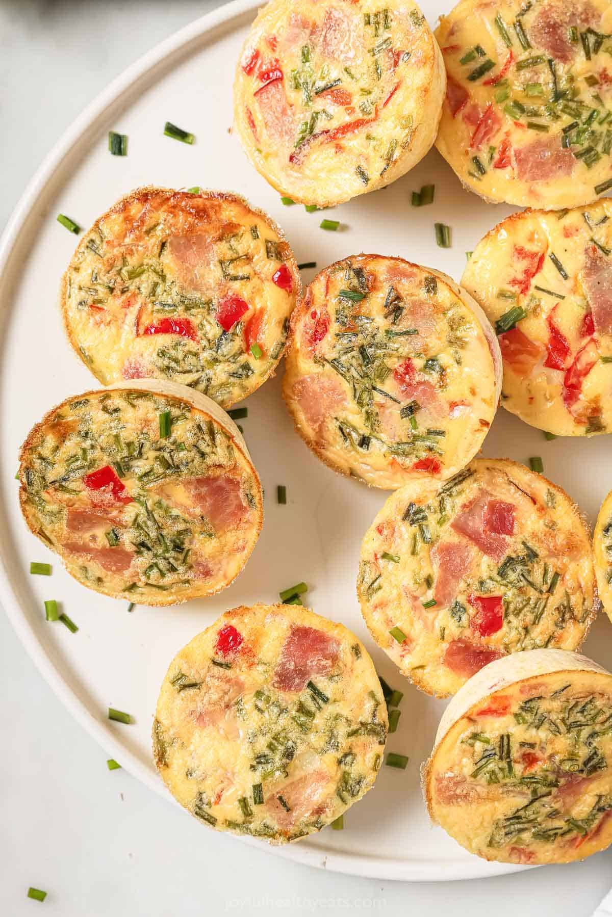 This 30-minute cottage cheese egg bites recipe with ham, tangy Dijon, and sweet roasted peppers is an easy on-the-go breakfast. Close-up of cottage cheese egg bites with ham, roasted peppers, and crunchy chives.