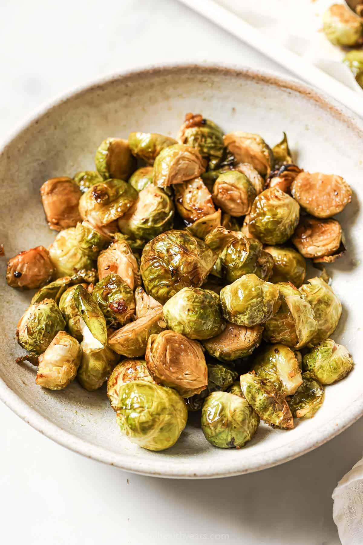 Honey Balsamic Brussels Sprouts are roasted to crispy perfection and jazzed up with a sweet, savory, and tangy sauce to make them extra tasty! Bowl of honey balsamic Brussels sprouts