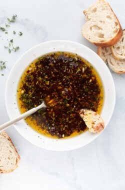 Overhead view of bread dipping oil in bowl with spoon