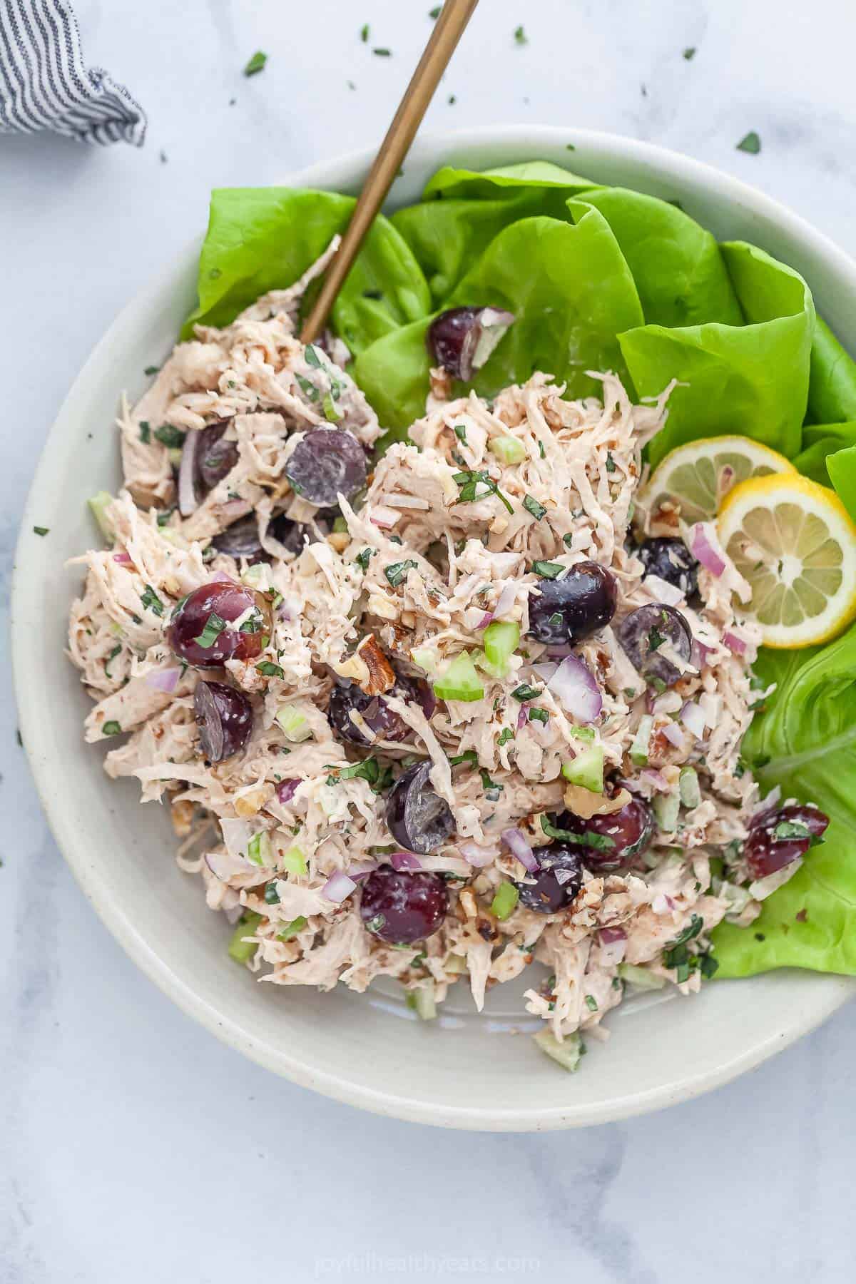 This Waldorf chicken salad recipe is perfect for meal prep lunches, picnics, or even a light dinner! It's easy to make and so delicious. Overhead view of Waldorf chicken salad in bowl with lettuce