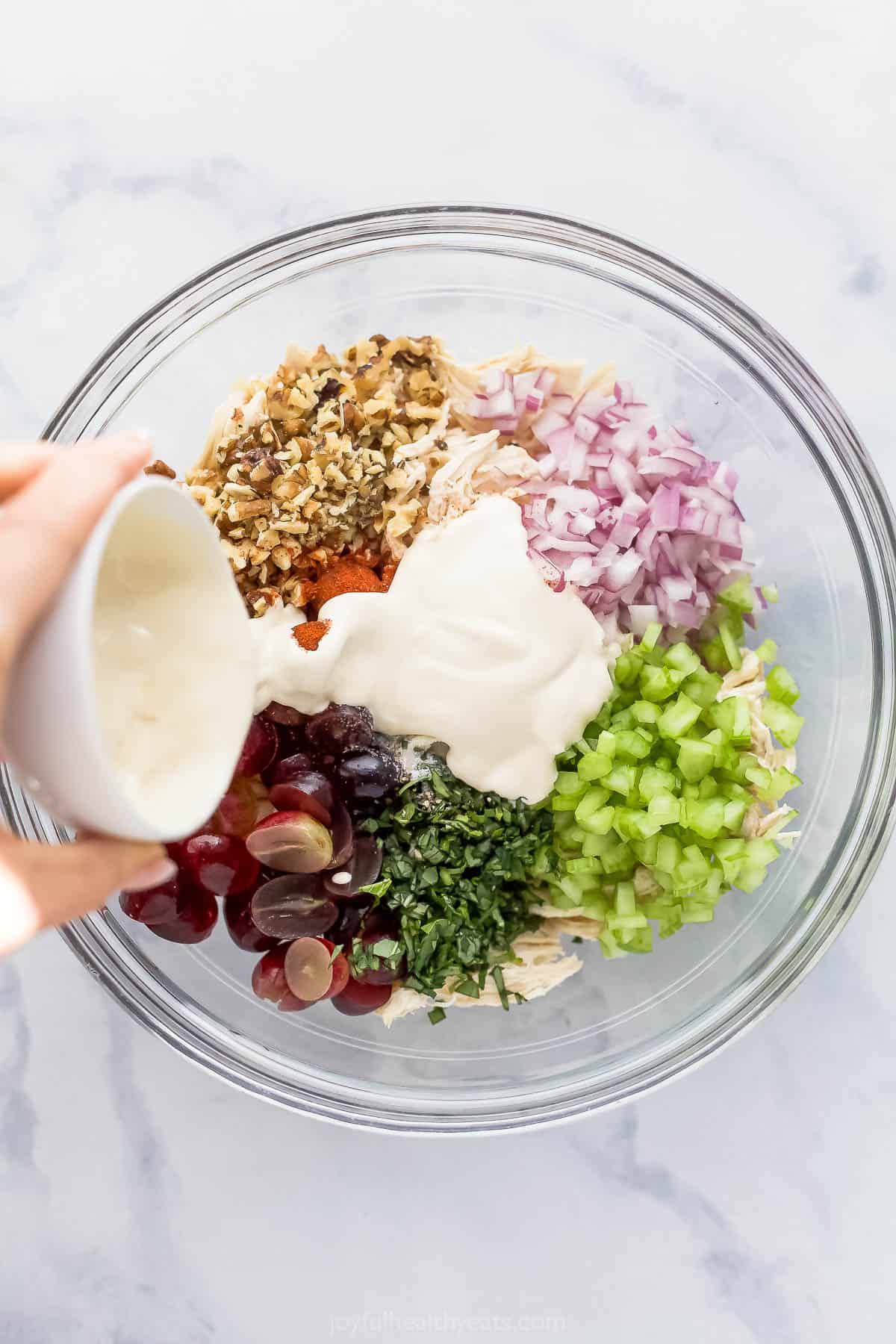 Pouring dressing into Waldorf chicken salad