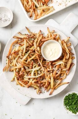 Overhead view of Parmesan truffle fries on platter with bowl of aioli