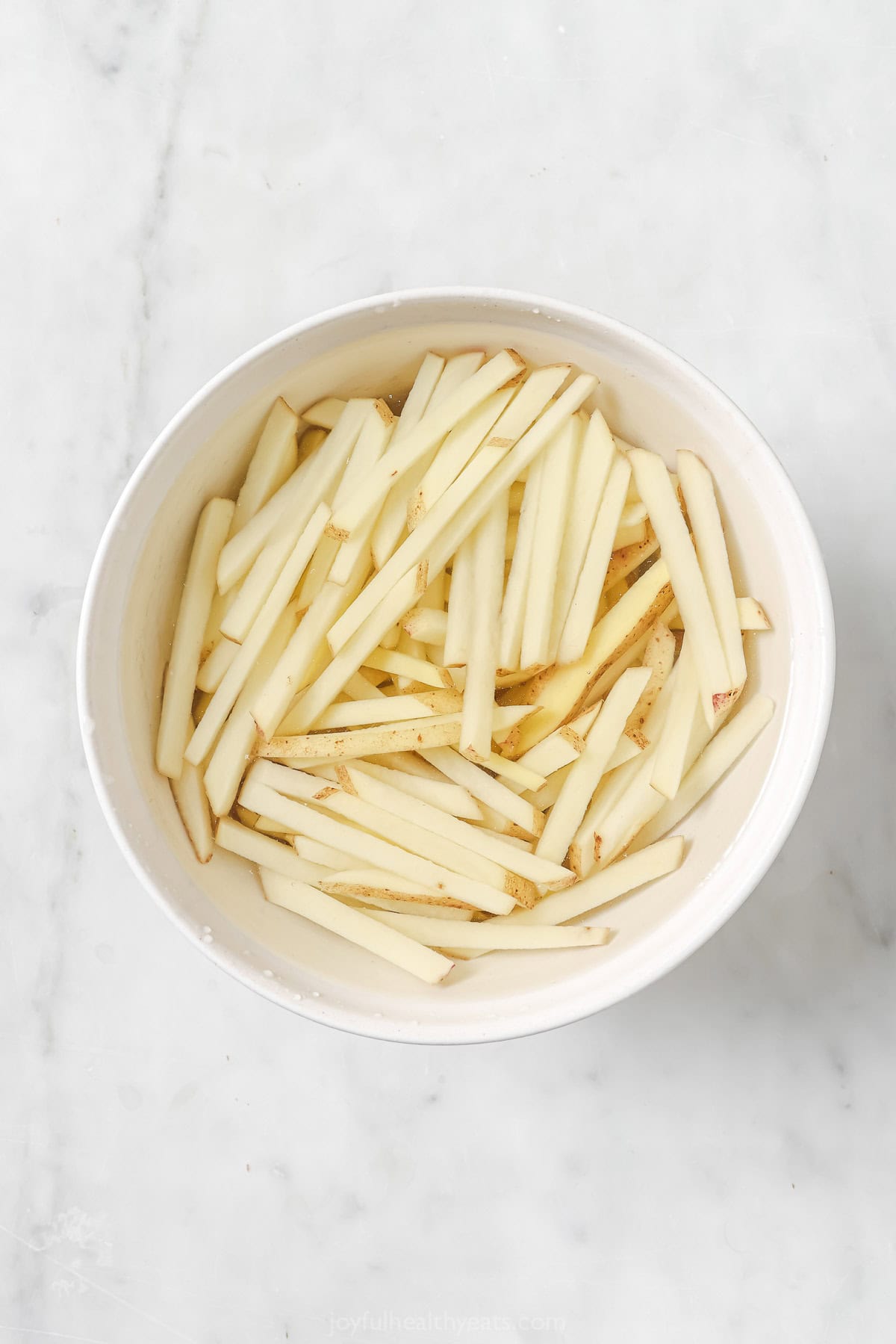 Raw fries soaking in bowl of water