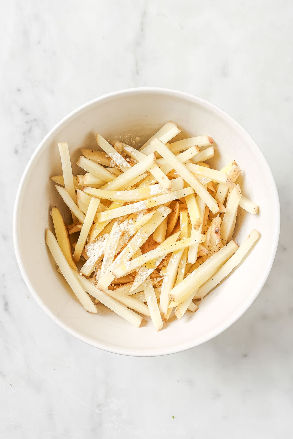 Seasonings added to bowl of uncooked fries