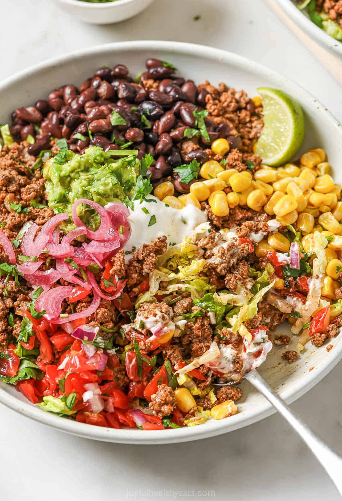 These taco salad bowls pack in all the deliciousness of a taco, minus the tortilla— seasoned beef, romaine, beans and your favorite toppings! Taco salad bowl with black beans, beef, and corn